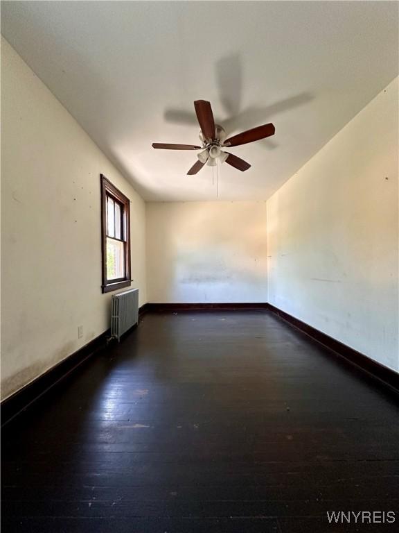 2010 Niagara St, Niagara Falls, NY 14303 - empty room with radiator heating unit, a ceiling fan, and dark wood finished floors
