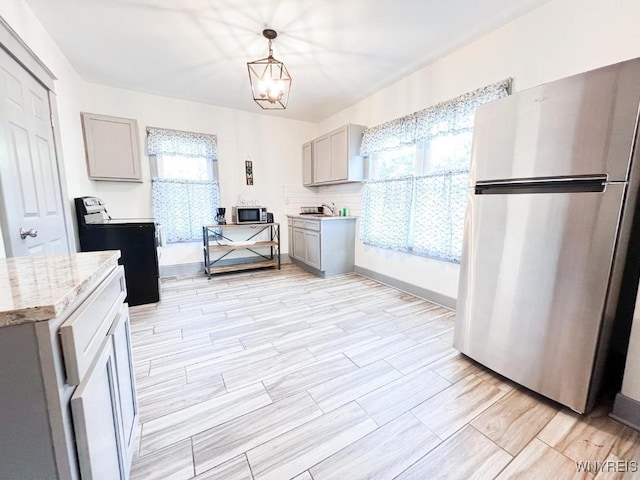2218 Ferry Ave, Niagara Falls, NY 14301 - kitchen featuring appliances with stainless steel finishes, gray cabinets, plenty of natural light, and decorative light fixtures