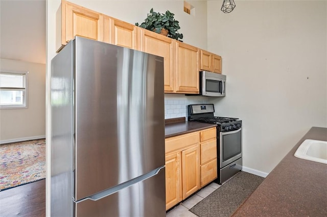 39 Castleford Rd, Greece, NY 14616 - kitchen featuring stainless steel appliances, dark countertops, light brown cabinetry, and tasteful backsplash