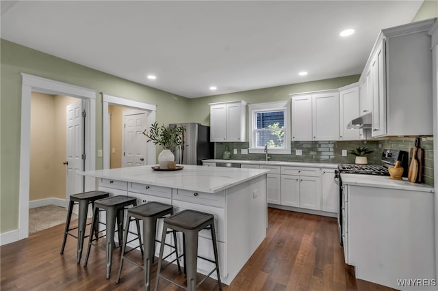 64 Sagamore Ter, Buffalo, NY 14214 - kitchen with under cabinet range hood, a kitchen island, freestanding refrigerator, backsplash, and a kitchen bar