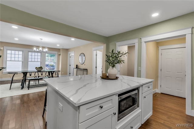 64 Sagamore Ter, Buffalo, NY 14214 - kitchen with stainless steel microwave, white cabinets, a kitchen island, dark wood finished floors, and a chandelier