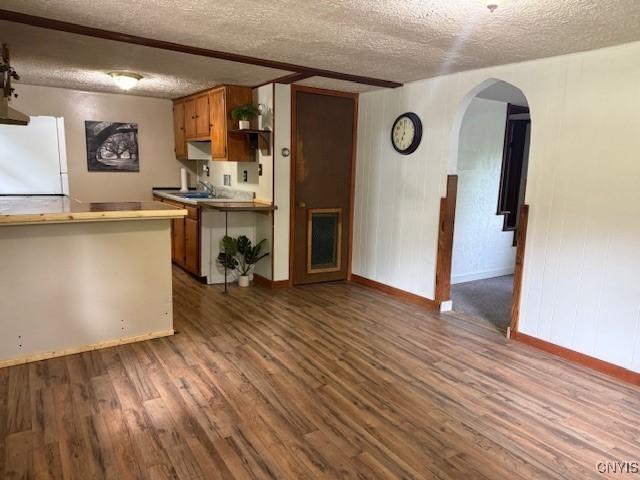 1086 Sweatman Ave, Oneida-Inside, NY 13421 - kitchen with freestanding refrigerator, a textured ceiling, arched walkways, wood finished floors, and brown cabinets