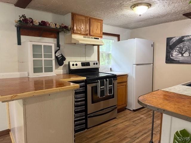 1086 Sweatman Ave, Oneida-Inside, NY 13421 - kitchen featuring stainless steel electric range oven, under cabinet range hood, freestanding refrigerator, brown cabinets, and wood finished floors
