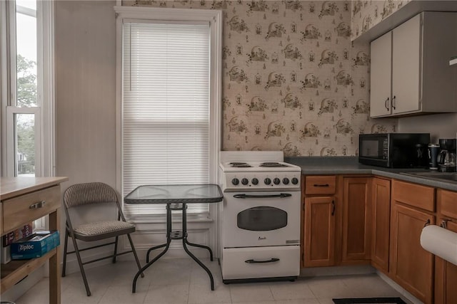 21 Washington St, Greene, NY 13778 - kitchen with white electric stove, black microwave, wallpapered walls, brown cabinets, and dark countertops