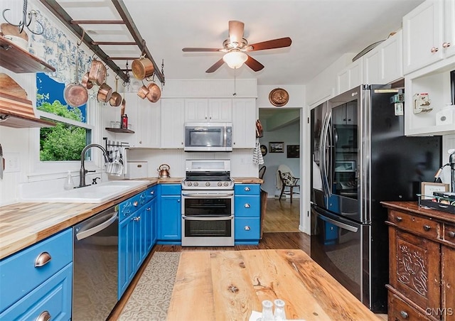 5458 Oxbow Rd, Cazenovia, NY 13035 - kitchen featuring blue cabinetry, stainless steel appliances, butcher block countertops, light wood-style flooring, and white cabinetry