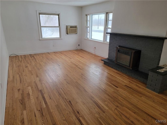 1665 State Route 31, Sullivan, NY 13037 - unfurnished living room featuring a wall mounted AC, wood finished floors, and a brick fireplace