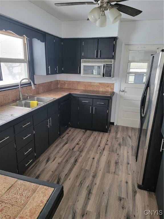 1665 State Route 31, Sullivan, NY 13037 - kitchen with stainless steel microwave, freestanding refrigerator, ceiling fan, light wood finished floors, and dark cabinets