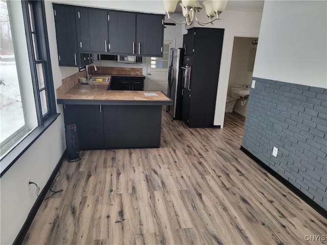 1665 State Route 31, Sullivan, NY 13037 - kitchen featuring a peninsula, light wood-style flooring, a chandelier, stainless steel appliances, and tile counters