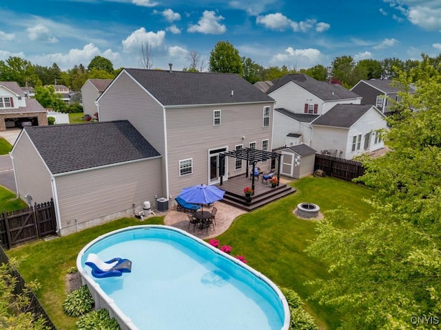 8228 Dampier Cir, Clay, NY 13090 - rear view of house featuring an outdoor fire pit, a wooden deck, outdoor dining area, a storage shed, and a fenced backyard
