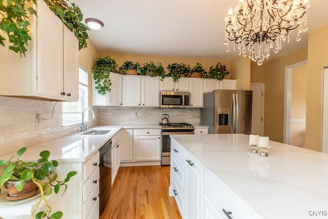 8228 Dampier Cir, Clay, NY 13090 - kitchen with stainless steel appliances, a chandelier, light countertops, white cabinetry, and light wood-style flooring