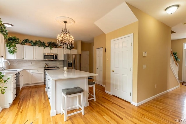 8228 Dampier Cir, Clay, NY 13090 - kitchen featuring appliances with stainless steel finishes, white cabinetry, light wood-style flooring, light countertops, and backsplash