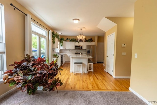 8228 Dampier Cir, Clay, NY 13090 - kitchen with stainless steel appliances, a chandelier, light countertops, a kitchen breakfast bar, and decorative light fixtures