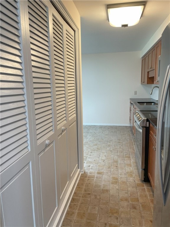 75 Towpath Ln, Brighton, NY 14618 - kitchen with stainless steel range with electric cooktop, dark countertops, brick patterned floors, and brown cabinetry