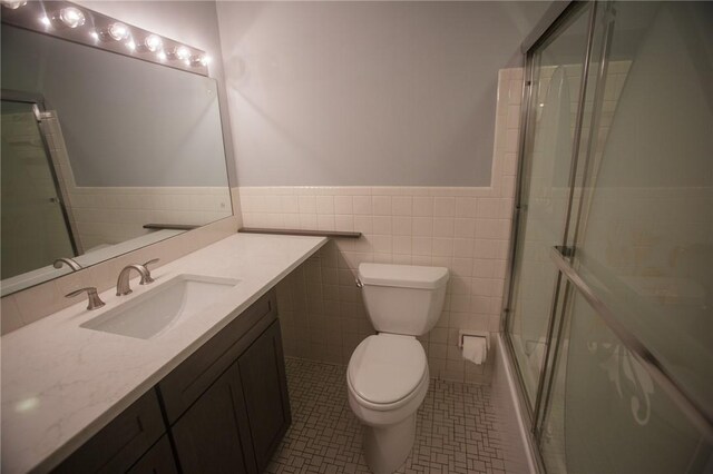 75 Towpath Ln, Brighton, NY 14618 - bathroom with tile walls, vanity, wainscoting, tile patterned flooring, and combined bath / shower with glass door