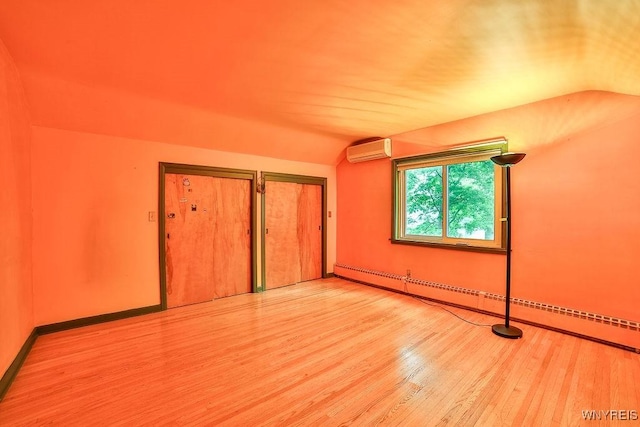 425 Tryon Dr, Lewiston, NY 14092 - unfurnished bedroom with lofted ceiling, wood finished floors, a baseboard heating unit, an AC wall unit, and a closet