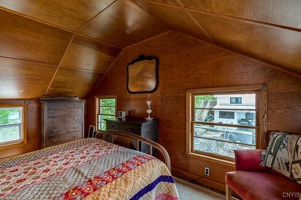 13 Mccabe Rd, Lisbon, NY 13669 - bedroom featuring vaulted ceiling, carpet flooring, and wood walls