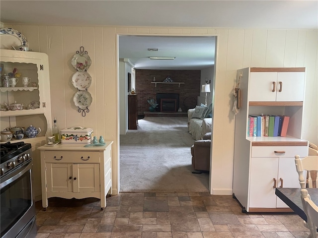 100 Huffer Rd, Parma, NY 14468 - kitchen featuring gas range, a brick fireplace, stone finish floors, light countertops, and white cabinetry
