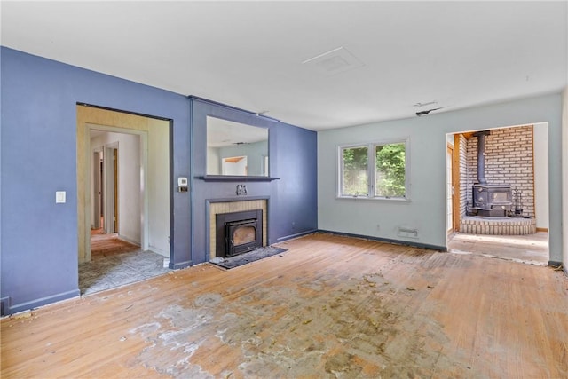 39 Scotch Ln, Irondequoit, NY 14617 - unfurnished living room featuring a wood stove and wood finished floors