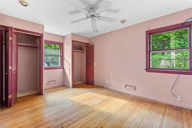 39 Scotch Ln, Irondequoit, NY 14617 - unfurnished bedroom featuring two closets, light wood-style flooring, and a ceiling fan