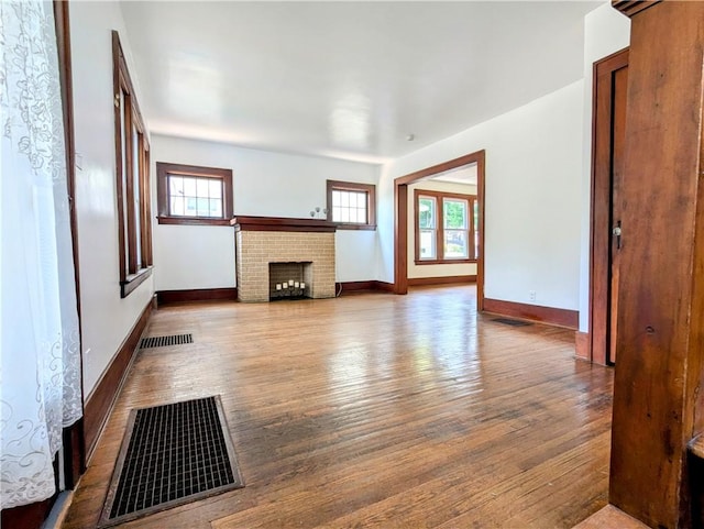 64 Saint Jacob St, Rochester, NY 14621 - unfurnished living room featuring healthy amount of natural light, wood finished floors, and a brick fireplace