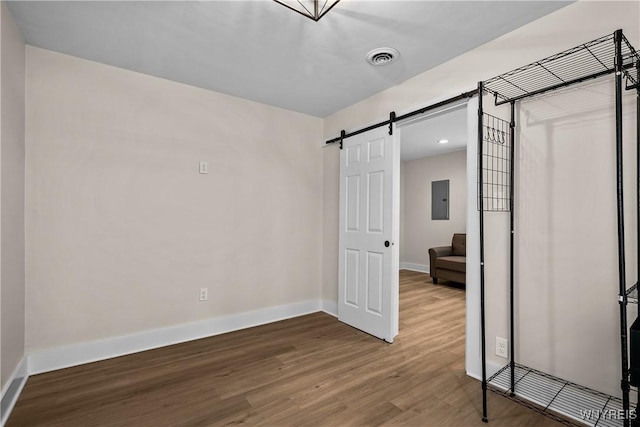 365 Oakdale Dr, North Tonawanda, NY 14120 - unfurnished bedroom featuring a barn door, wood finished floors, and electric panel