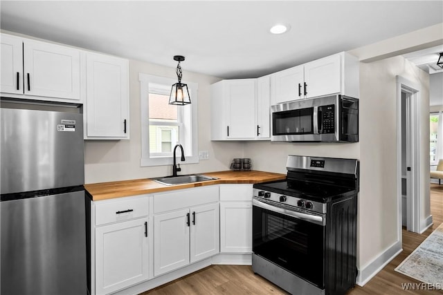 365 Oakdale Dr, North Tonawanda, NY 14120 - kitchen with appliances with stainless steel finishes, wood counters, light wood-style flooring, white cabinets, and hanging light fixtures