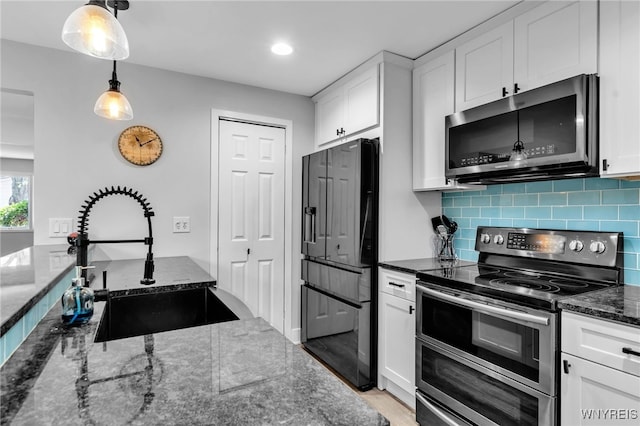 1202 Netherton Ct, Amherst, NY 14051 - kitchen featuring appliances with stainless steel finishes, white cabinetry, dark stone counters, tasteful backsplash, and hanging light fixtures