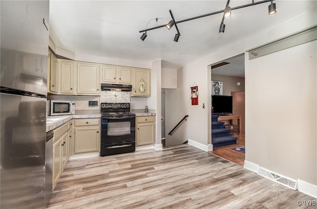 7042 Forbes Rd, Lenox, NY 13032 - kitchen with freestanding refrigerator, black range with electric stovetop, under cabinet range hood, and cream cabinets