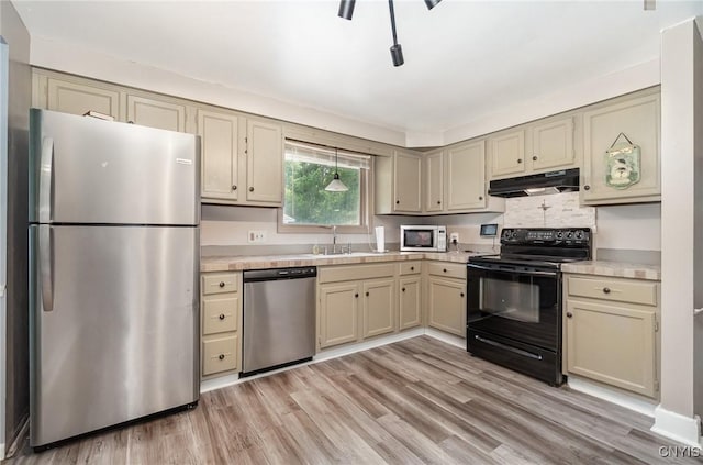 7042 Forbes Rd, Lenox, NY 13032 - kitchen with stainless steel appliances, under cabinet range hood, cream cabinets, light countertops, and light wood-style floors