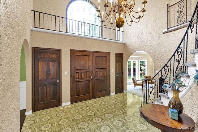 212 Crestwood Ln, Amherst, NY 14221 - foyer entrance with arched walkways, stairway, a chandelier, a textured wall, and a high ceiling