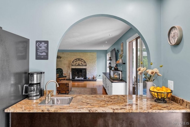 212 Crestwood Ln, Amherst, NY 14221 - kitchen featuring a brick fireplace, wood finished floors, stone countertops, arched walkways, and open floor plan