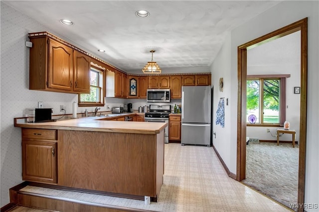 3851 Upper Mountain Rd, Cambria, NY 14132 - kitchen featuring stainless steel appliances, a peninsula, brown cabinetry, light countertops, and light carpet
