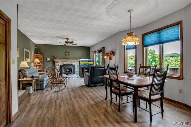 3851 Upper Mountain Rd, Cambria, NY 14132 - dining area featuring a ceiling fan, wood finished floors, a textured ceiling, and a stone fireplace