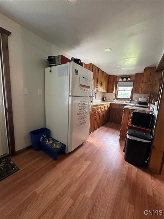 14309 Pearl St, Diana, NY 13648 - kitchen featuring freestanding refrigerator, brown cabinetry, light countertops, and light wood finished floors