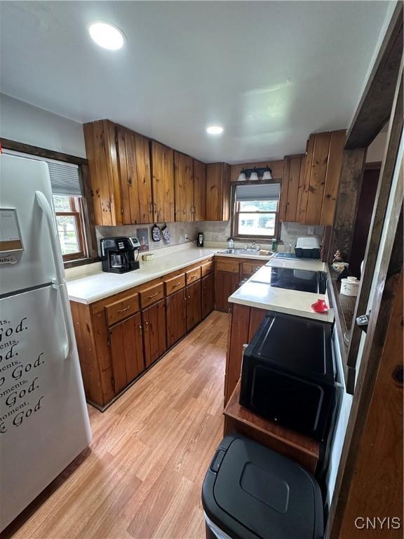 14309 Pearl St, Diana, NY 13648 - kitchen with freestanding refrigerator, brown cabinetry, light wood finished floors, light countertops, and recessed lighting