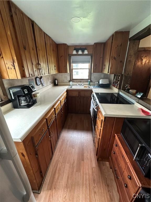 14309 Pearl St, Diana, NY 13648 - kitchen featuring light wood finished floors, brown cabinets, light countertops, and electric stove