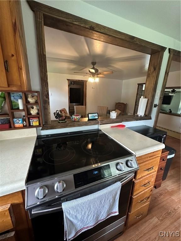 14309 Pearl St, Diana, NY 13648 - kitchen featuring stainless steel electric range oven, a ceiling fan, light countertops, brown cabinets, and wood finished floors