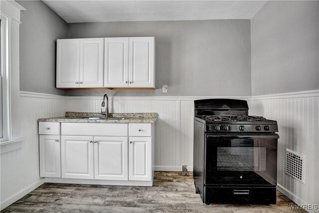 110 Weyand Ave, Buffalo, NY 14210 - kitchen featuring black gas stove, wainscoting, white cabinets, light stone counters, and wood finished floors