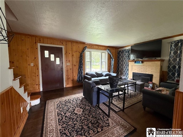 67 Harriet St, Allegany, NY 14706 - living room featuring a textured ceiling, wood walls, a fireplace, wood finished floors, and stairway