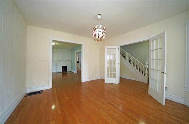 362 Euclid Ave, Elmira-City, NY 14905 - empty room with french doors, wood finished floors, a chandelier, and stairway