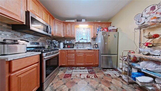 900 Sherman Pl, Utica, NY 13502 - kitchen with appliances with stainless steel finishes, backsplash, and brown cabinetry