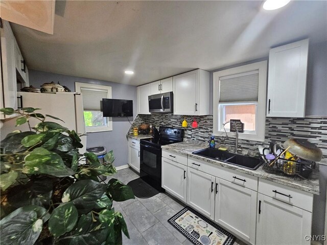 6 Bryant St, Utica, NY 13502 - kitchen with black range with electric cooktop, stainless steel microwave, backsplash, and white cabinetry
