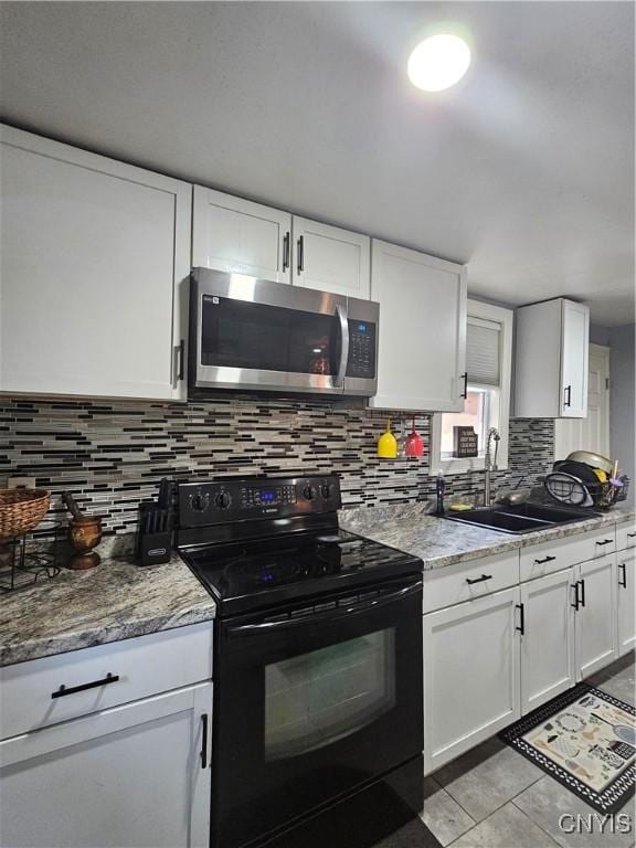 6 Bryant St, Utica, NY 13502 - kitchen with stainless steel microwave, black range with electric cooktop, white cabinetry, and decorative backsplash