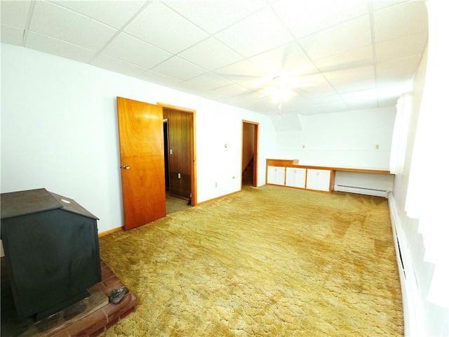 4883 Pinecrest Rd, Veteran, NY 14864 - spare room featuring a drop ceiling, baseboard heating, carpet floors, and a wood stove