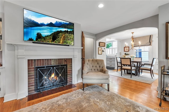 87 Garrison Rd, Amherst, NY 14221 - living area featuring arched walkways, wood finished floors, a brick fireplace, a chandelier, and recessed lighting
