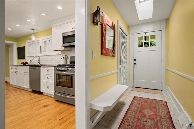 3864 Bristol Rd, Kirkland, NY 13323 - kitchen with appliances with stainless steel finishes, white cabinets, dark countertops, decorative backsplash, and a skylight