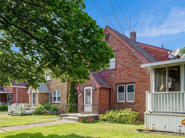 2776 Forest Ave, Niagara Falls, NY 14303 - view of front facade with brick siding, a front yard, a chimney, a shingled roof, and a sunroom