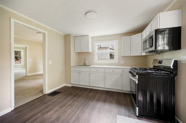 37 Nelson St, Auburn, NY 13021 - kitchen featuring appliances with stainless steel finishes, dark wood-style floors, healthy amount of natural light, white cabinetry, and ornamental molding
