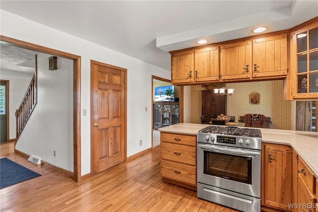 8345 Lapp Rd, Clarence, NY 14051 - kitchen with stainless steel gas range, light countertops, light wood-type flooring, a peninsula, and glass insert cabinets