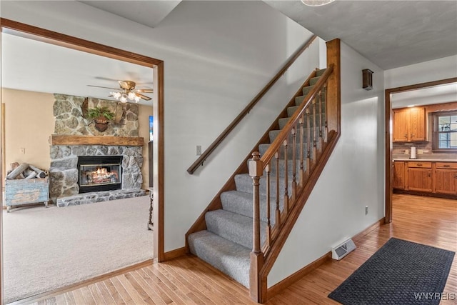 8345 Lapp Rd, Clarence, NY 14051 - stairway featuring wood finished floors, a ceiling fan, and a fireplace
